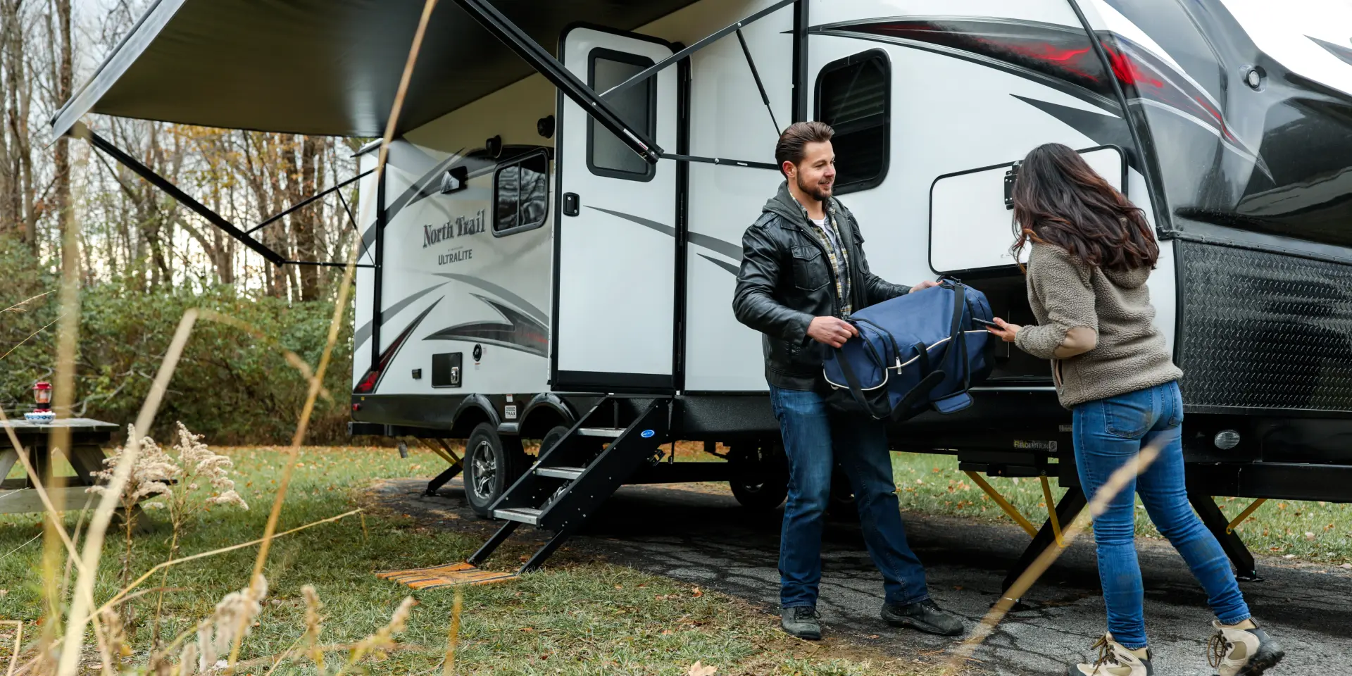 A man and a woman taking a travel bag out of a campervan