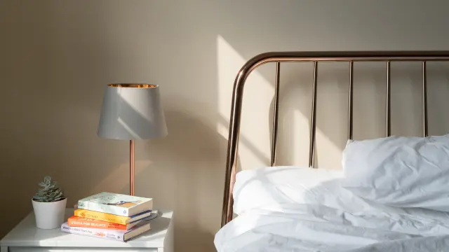 Lit avec une tête de lit en métal et une lampe de chevet à côté d'une pile de livres