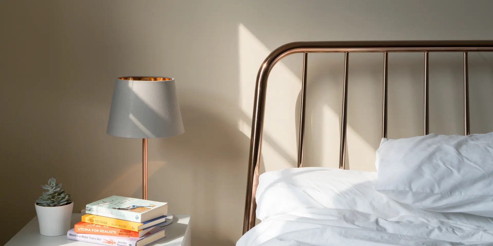 Lit avec une tête de lit en métal et une lampe de chevet à côté d'une pile de livres