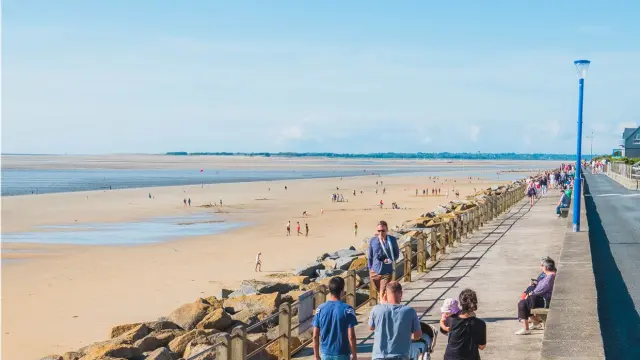 Menschen spazieren auf einer Meerespromenade mit einem Sandstrand