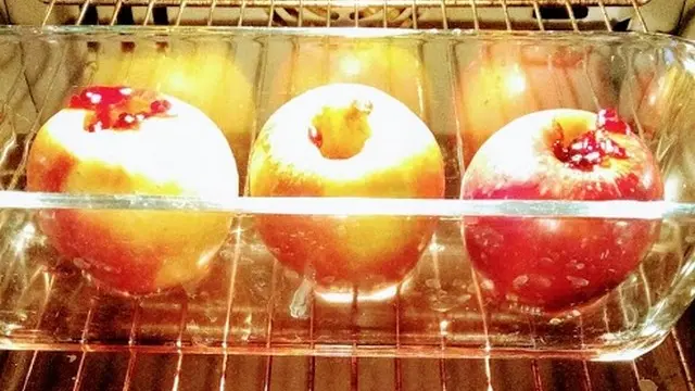 Trois pommes avec des trous au centre cuisent dans un four