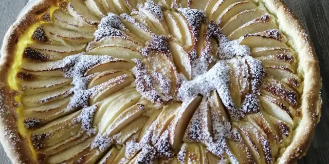 Apfelkuchen mit goldener Kruste und Äpfeln in einer Rosette angeordnet