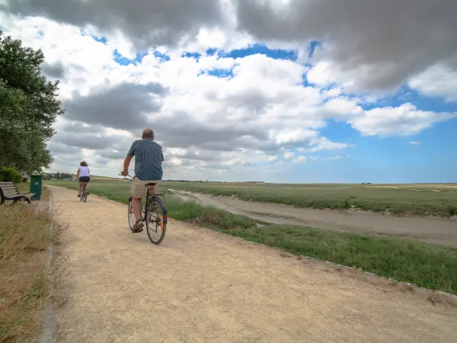 Deux personnes à vélo sur un chemin au bord du havre de Regneville