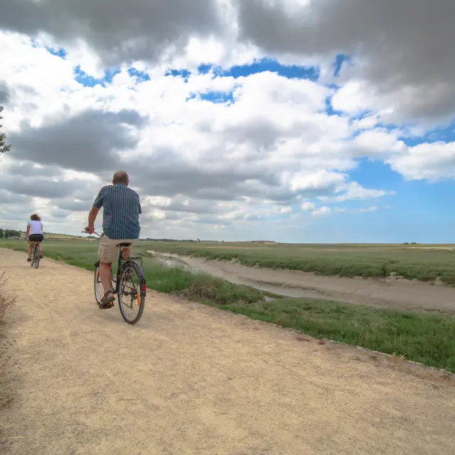 Deux personnes à vélo sur un chemin au bord du havre de Regneville