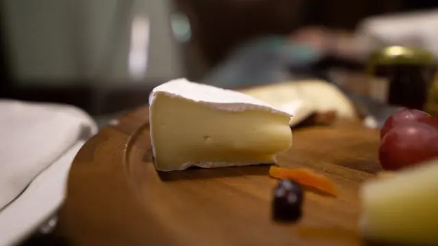 Assiette en bois avec du fromage, des raisins et des carottes