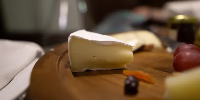 Holzplatte mit Käse, Trauben und Karotten