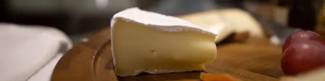 Assiette en bois avec du fromage, des raisins et des carottes