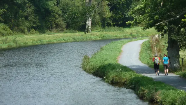 Zwei Personen gehen einen Weg entlang neben einem Kanal