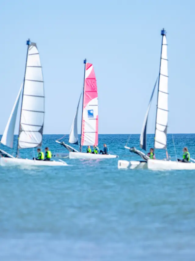 Three sailboats competing on blue water