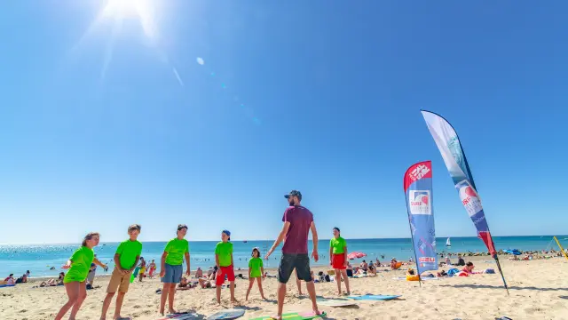 A group of people taking surf lessons on a sunny beach