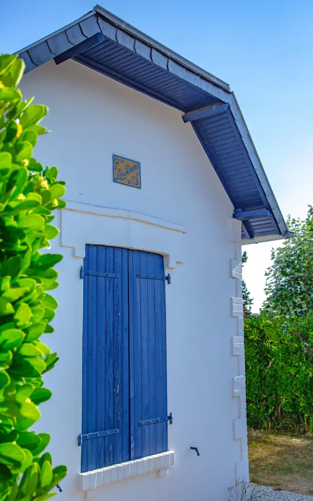 Kleines weißes Haus mit blauen Fensterläden und grauem Dach