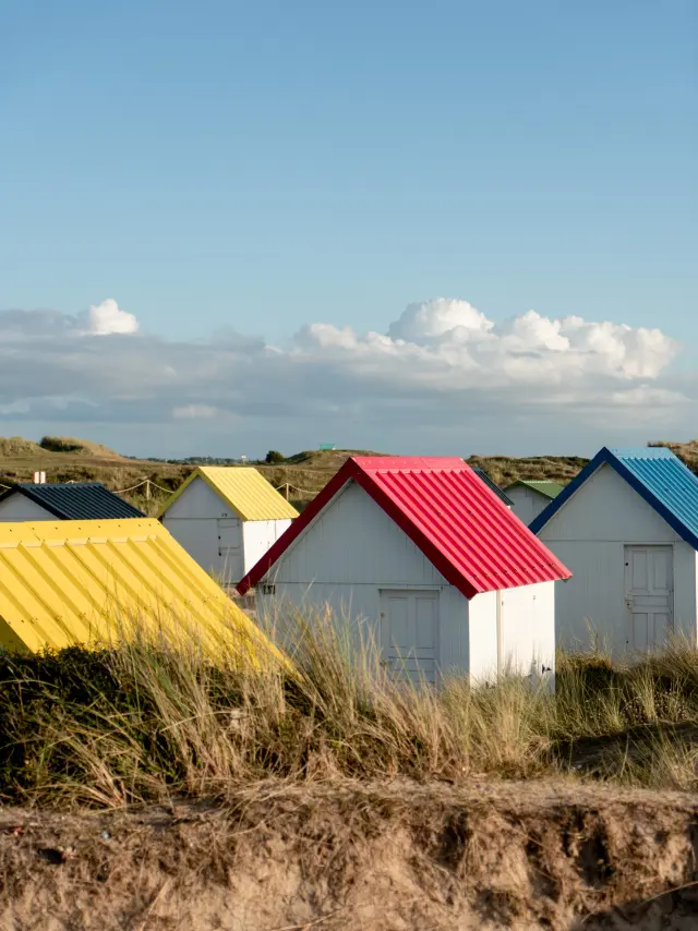 Several beach huts with roofs of different colors