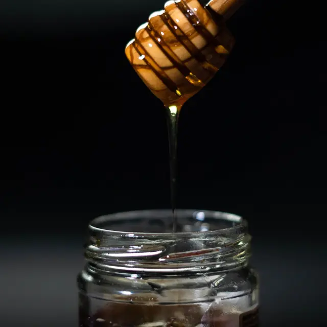 Miel doré s'écoulant d'un pot en verre