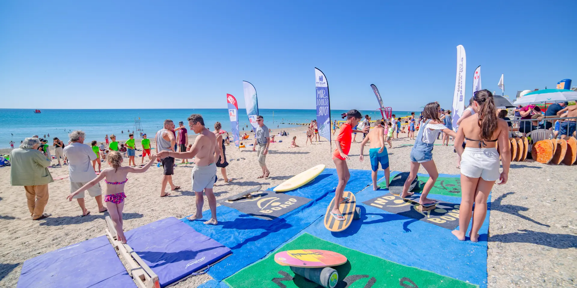 Personnes participant à un événement de surf sur une plage ensoleillée à Agon-Coutainville
