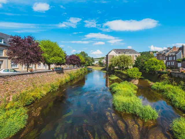 A calm river runs through a town with houses and trees on both sides