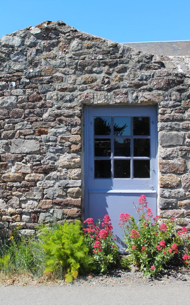 Blue wooden door with red and green flowers next to it
