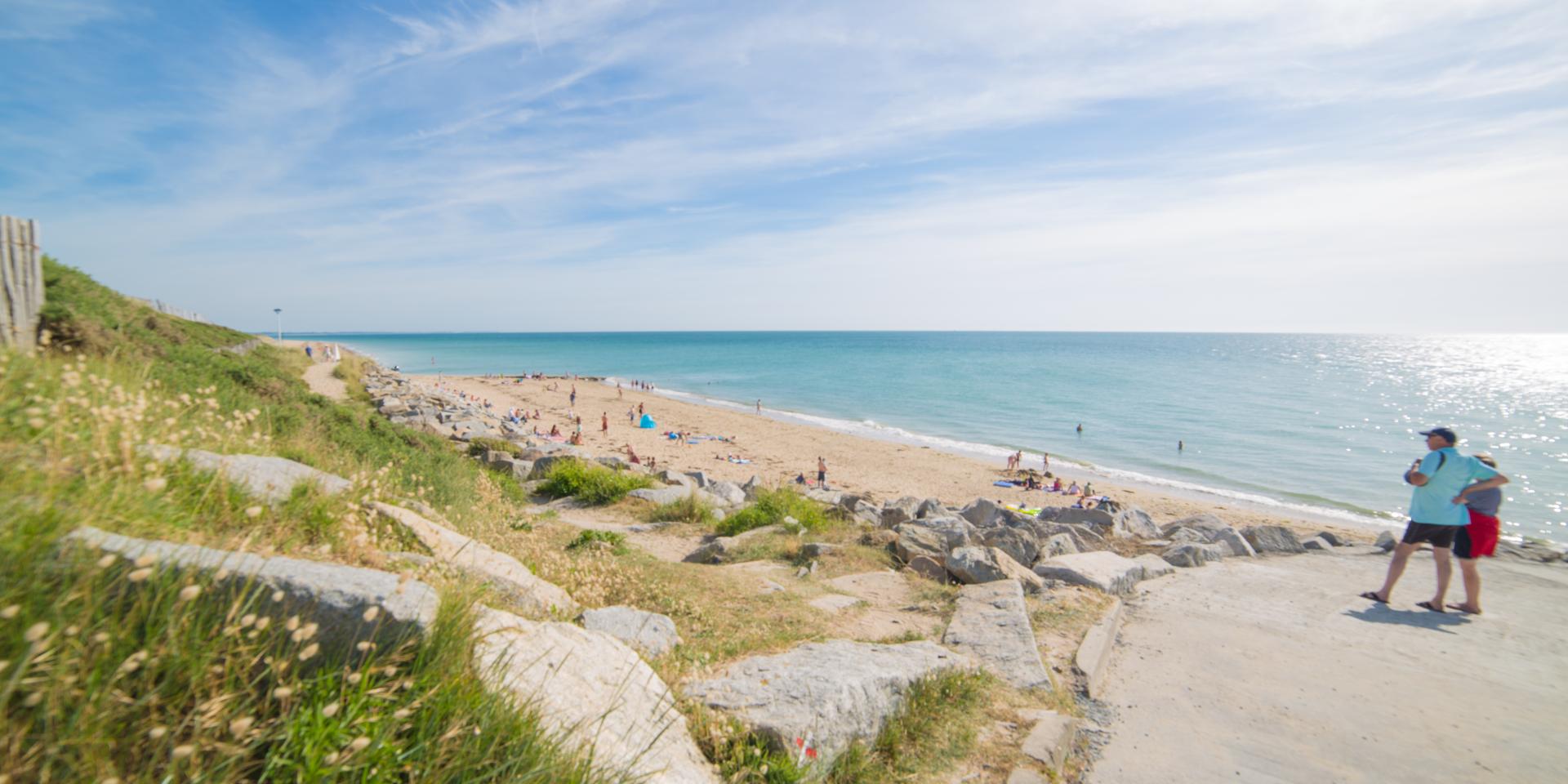 Two people walking on a beach path with a view of the sea