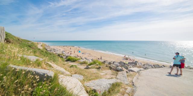 Deux personnes marchent sur un chemin de plage avec vue sur la mer
