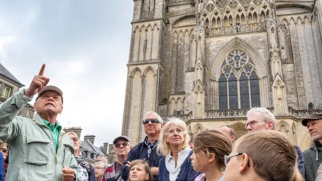 Un groupe de personnes écoutant un guide devant la cathédrale de Coutances
