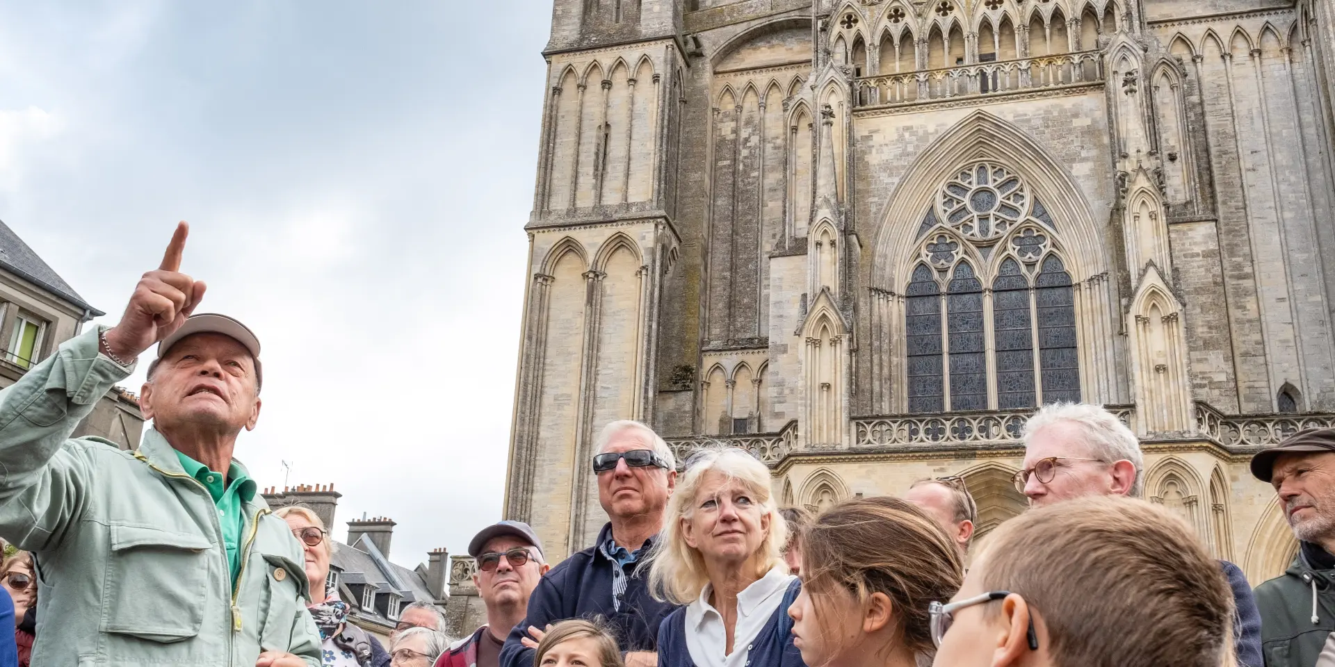 Un groupe de personnes écoutant un guide devant la cathédrale de Coutances