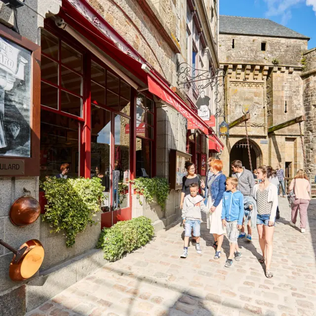 A family walks in front of a restaurant with a sign 'LA MÈRE POULARD'