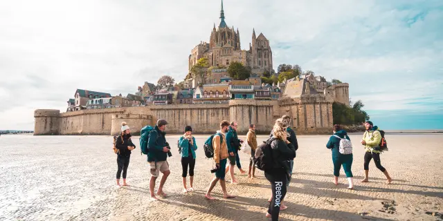 Group of hikers walking on the beach towards Mont Saint-Michel