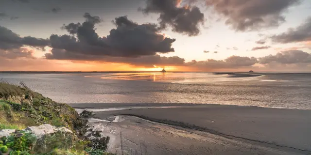 Sunset on a deserted beach with waves and clouds