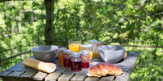 Table en bois avec des aliments pour le petit-déjeuner à la cabane dans les arbres de Savigny
