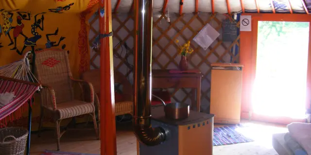 Intérieur d'une yourte avec un poêle à bois, des chaises et des décorations murales