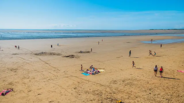 People walking on a sandy beach with the ocean in the background