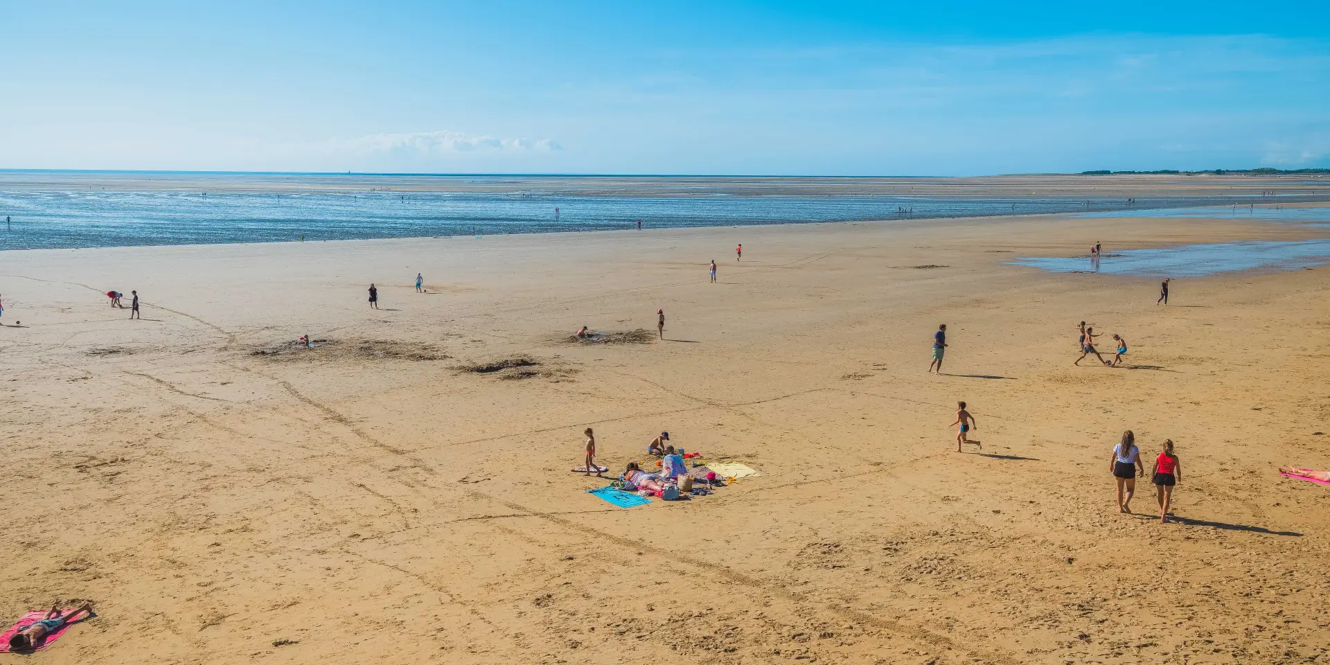 People walking on a sandy beach with the ocean in the background