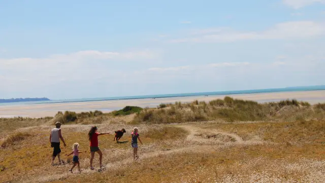 A family walks on a grassy hill near the sea