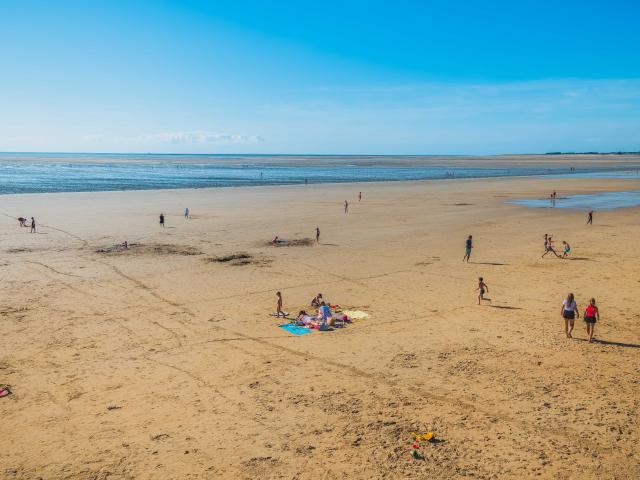 People walking on a sandy beach with the ocean in the background