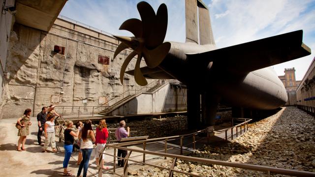 Group of people visiting a maritime museum with a ship's propeller on display