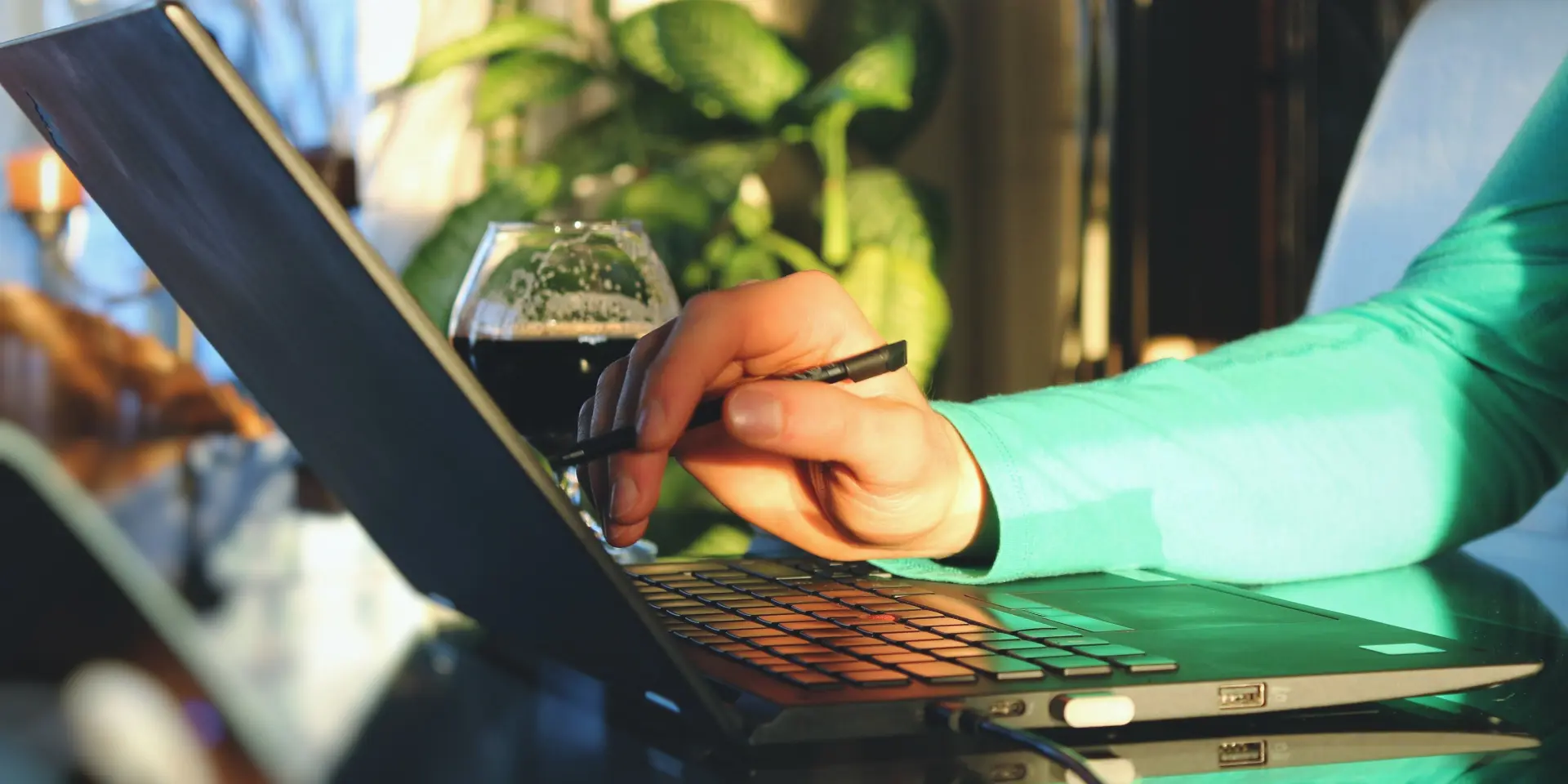 Personne travaillant sur un ordinateur portable avec un verre de bière à côté