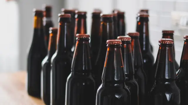 Bouteilles de bière brune alignées sur un comptoir en bois