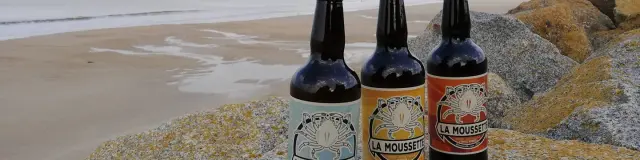 Trois bouteilles de bière La Moussette sur des rochers près de la plage