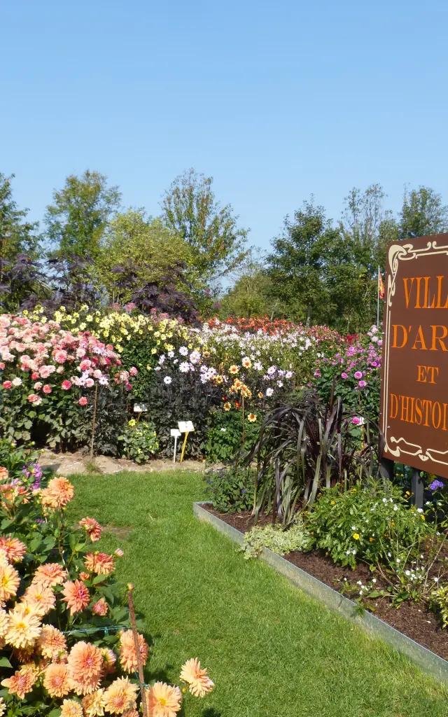 Jardin fleuri avec un panneau Ville d'Art et d'Histoire : festival des dahlias de Coutances
