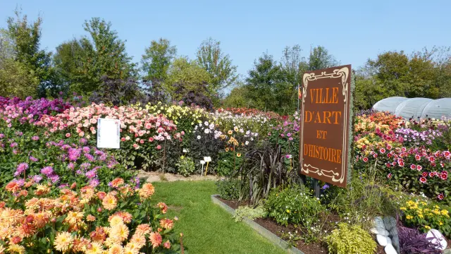 Jardin fleuri avec un panneau Ville d'Art et d'Histoire : festival des dahlias de Coutances