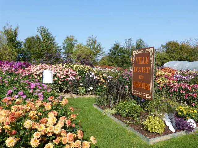 Jardin fleuri avec un panneau Ville d'Art et d'Histoire : festival des dahlias de Coutances