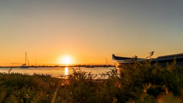 Coucher de soleil sur l'eau avec des bateaux en arrière-plan dans le havre de Regnéville