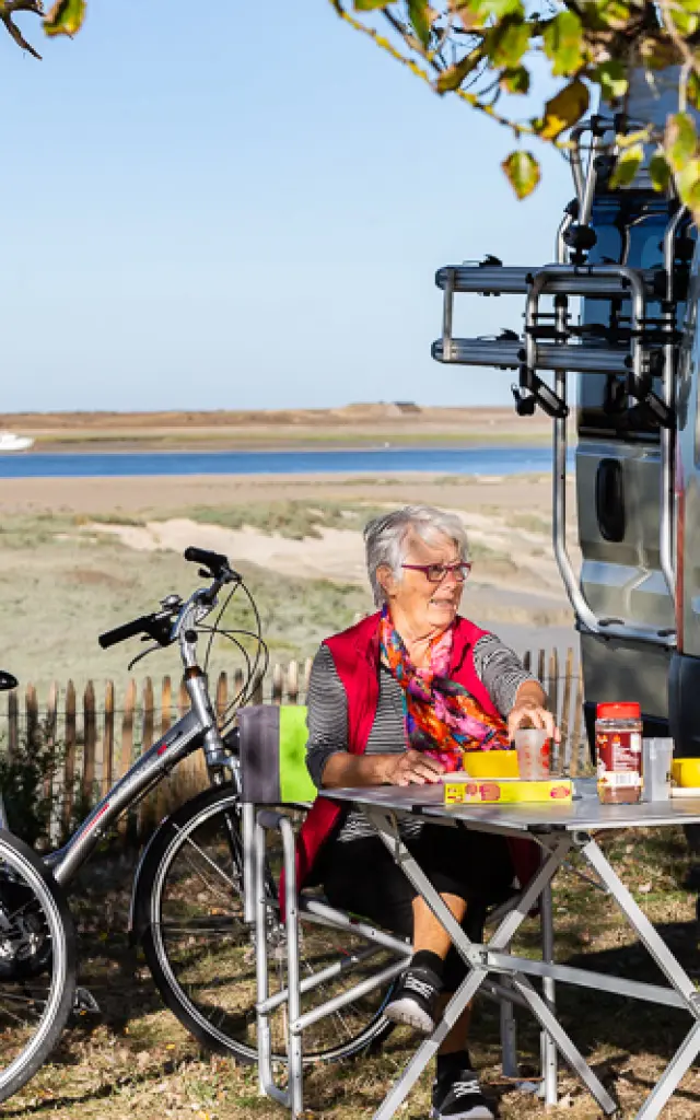 Deux personnes pique-niquent près d'un plan d'eau avec des vélos à proximité