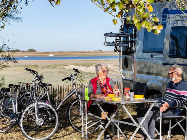 Deux personnes pique-niquent près d'un plan d'eau avec des vélos à proximité