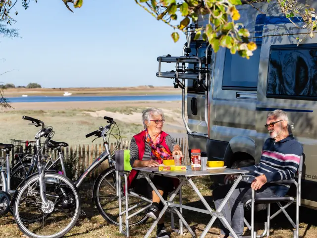 Deux personnes pique-niquent près d'un plan d'eau avec des vélos à proximité