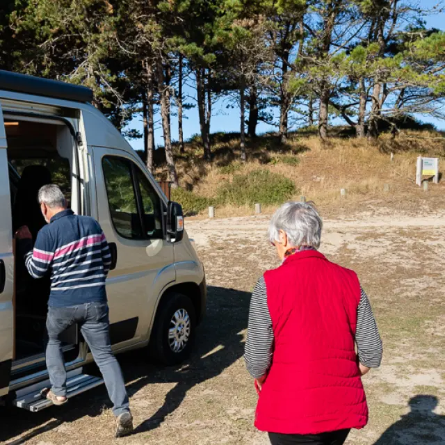 Un couple âgé sort d'un camping-car sur une parking