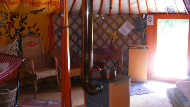 Intérieur d'une yourte avec un poêle, des chaises et des décorations murales