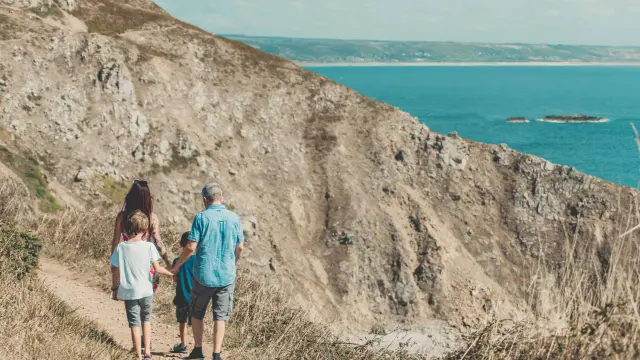 A family walks on a hiking trail near a cliff