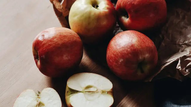 Pommes fraîches posées sur une table en bois avec des morceaux coupés