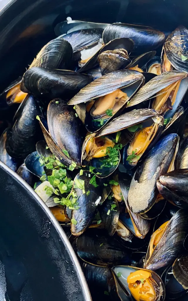 Moules cuites dans un pot avec des herbes vertes