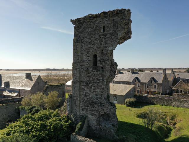 Medieval tower in ruins with houses in the background